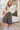 Woman in a floral dress and white cardigan standing in a living room.