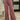A person wearing dusty rose wide-leg drawstring pants with patchwork paneling and beige slip-on shoes, standing on a patterned rug in an indoor room setting.