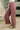 A person wearing dusty rose wide-leg corduroy pants with a drawstring waist, styled with beige shoes in a cozy indoor setting.