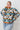 Person wearing a patterned sweater with a white tiled background