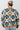 Person wearing a patterned sweater with a white tiled wall background