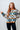 Woman wearing a patterned sweater against a white tiled wall