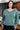 Woman wearing a teal sweater in an indoor setting
