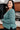 Woman wearing a teal sweater in an indoor setting
