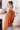 Woman wearing a rust-colored sweater in a kitchen setting