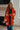 Woman wearing an orange cardigan with white floral patterns in a room.