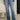 Person wearing blue jeans with a floral top in an indoor setting