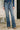 Person wearing blue jeans with a floral top in an indoor setting