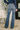 Person wearing blue jeans and a patterned top in an indoor setting