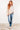 Woman wearing a striped sweater and jeans against a white wall