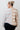 Person wearing a checkered sweater with a white tiled wall background