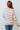 Person wearing a striped sweater with a white tiled wall background