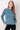 Woman wearing a blue cable knit sweater against a white background