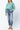 A model wearing Judy Blue High Waisted Release Hem Ankle Straight Leg Jeans, full-length front view showcasing a mint green top and distressed detailing.