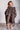 Child wearing a leopard print robe against a white brick wall.
