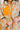 Person wearing a floral coat with orange flowers on a light green background