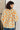 Person wearing a light green cardigan with orange floral patterns against a neutral background