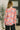 Woman wearing a colorful floral blouse in an indoor setting.
