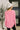Person wearing a pink long-sleeve top and white beanie indoors.