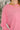 Close-up of a person wearing a pink long-sleeve shirt with gold necklaces.