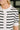 Close-up of a person wearing a white short-sleeve knit top with black horizontal stripes, a ruffled collar, and a ruffled button placket.