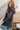 Woman wearing a dark gray oversized sweater and jeans sitting on a staircase.