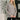 Woman wearing a gray sweater standing indoors with decorative elements in the background