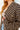 Person wearing a black and beige checkered shirt with a blurred background