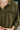 Person wearing an olive green button-up shirt with a blurred background