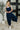 Woman wearing a navy jumpsuit with a white background