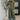 A woman modeling a long-sleeve, high-neck, olive green knit cowl-neck sweater with a front slit, styled with wide-leg blue jeans and brown shoes in a modern indoor setting.