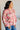 Woman wearing a floral blouse with a white brick wall background